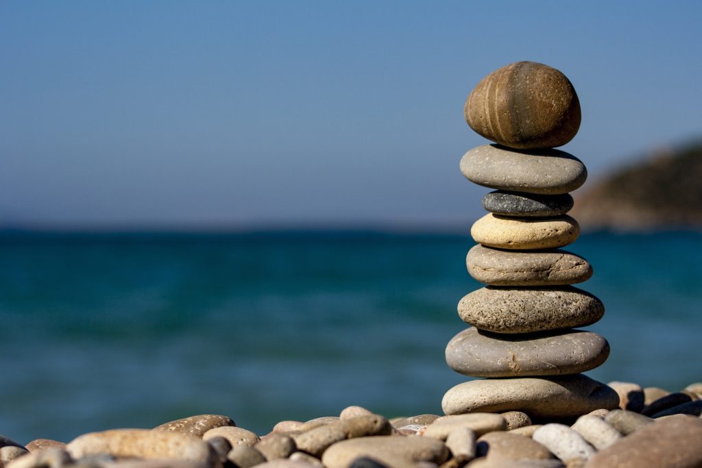 A stack of rocks on a beach, promoting relaxation therapy and holistic wellness.