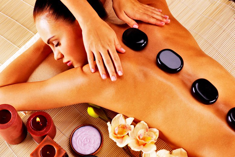 A woman experiencing tranquil healing during a hot stone massage at a spa.