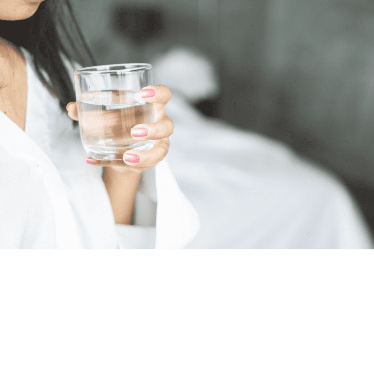 Ar Holistic Therapy - Bradford - A woman practicing healthy habits in life by holding a glass of water in bed.