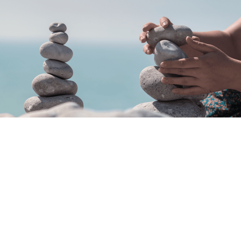 Ar Holistic Therapy - Bradford - A patient woman delicately balances stones on the beach.