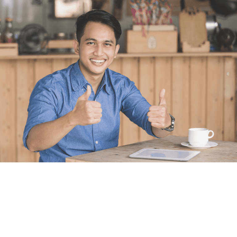 Ar Holistic Therapy - Bradford - A man giving a thumbs up, exuding lasting happiness, while sitting at a table with a cup of coffee.