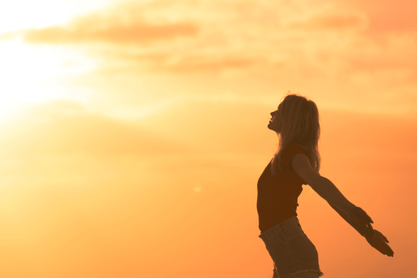 Ar Holistic Therapy - Bradford - A satisfied woman is standing on top of a hill with her arms outstretched.