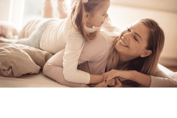 Ar Holistic Therapy - Bradford - A mother and daughter enjoying a good moment as they lay on a bed together.